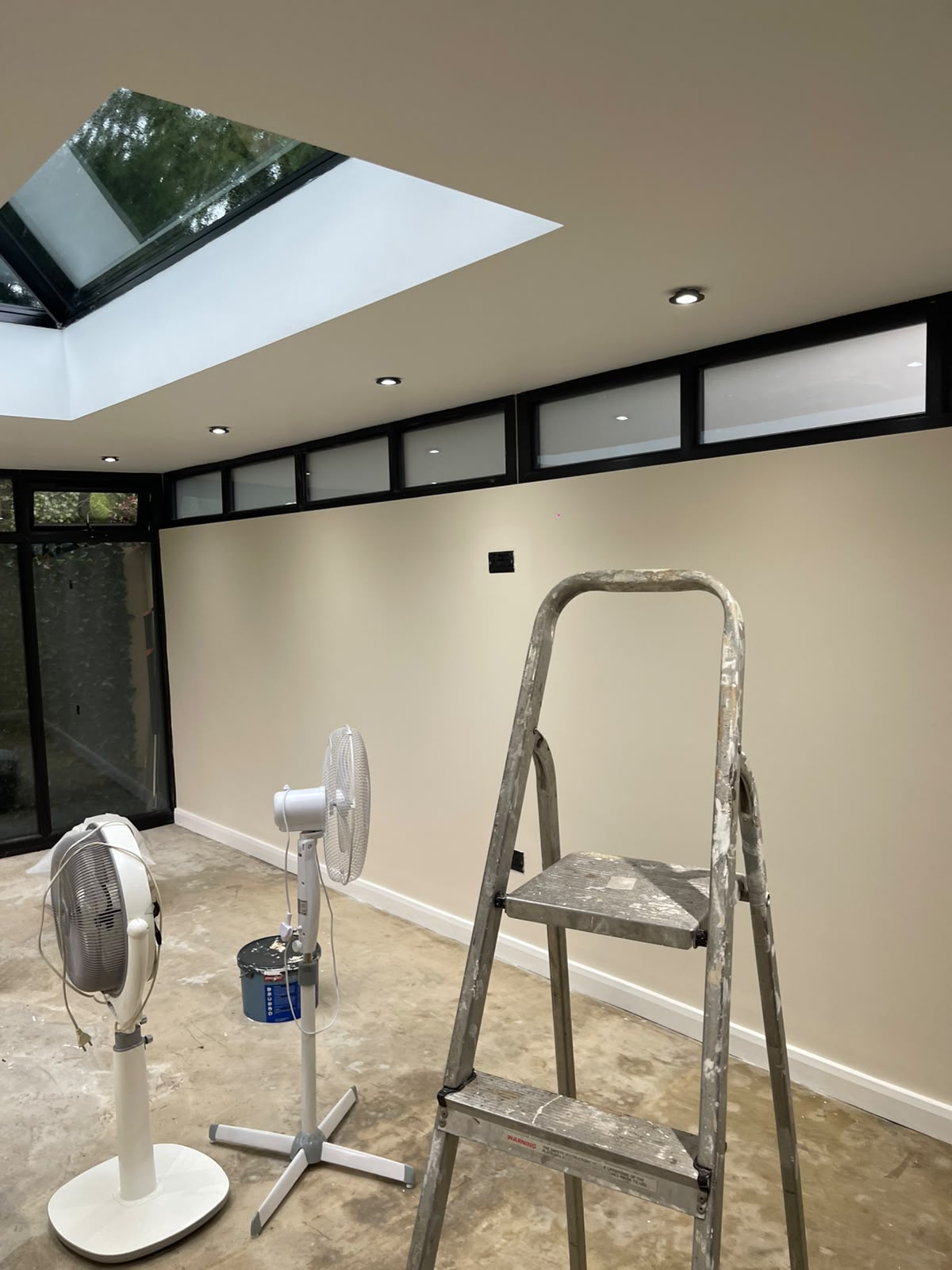 Freshly painted sunroom wall beneath black clerestory windows