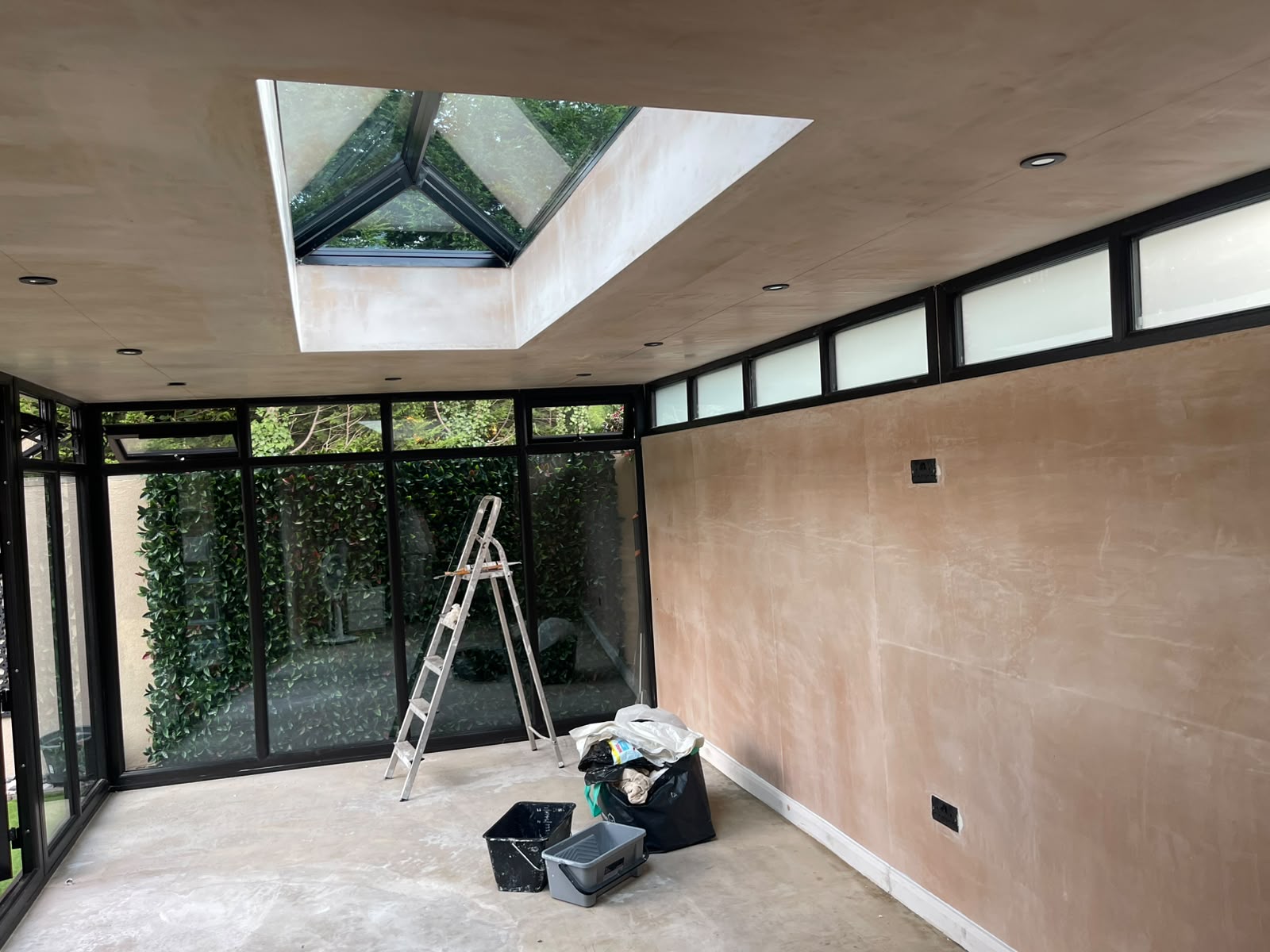 Sunroom before painting with plaster walls, roof lantern and black window frames